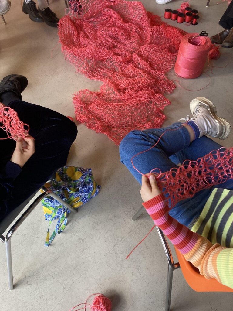 Ein großes rotes Netz wird beim Sangre de mi Sangre Workshop gestrickt